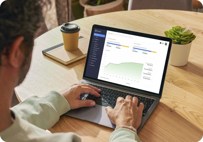 Una persona revisa sus finanzas en Zoho Books en la mesa de un café
